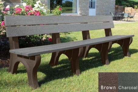 Traditional 8 foot commercial outdoor bench made out of 100% recycled plastic. This bench is made with our durable 2"x6" planks and perfect for parks and trails. Shown with a brown frame and charcoal boards on grass with flowers behind it.