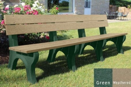 Traditional 8 foot commercial outdoor bench made out of 100% recycled plastic. This bench is made with our durable 2"x6" planks and perfect for parks and trails. Shown with a green frame and weathered boards on grass with flowers behind it.
