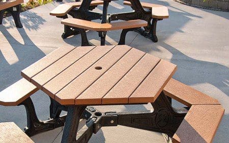Lansing Center patio with Plaza hexagonal tables and Elitel 8 ft backed benches, all with black frames and cedar colored planks for seats, tabletops and benches.