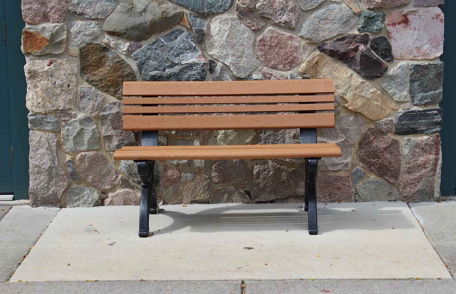 Cambridge 4ft backed bench resting against stone wall in downtown Grand Ledge Michigan