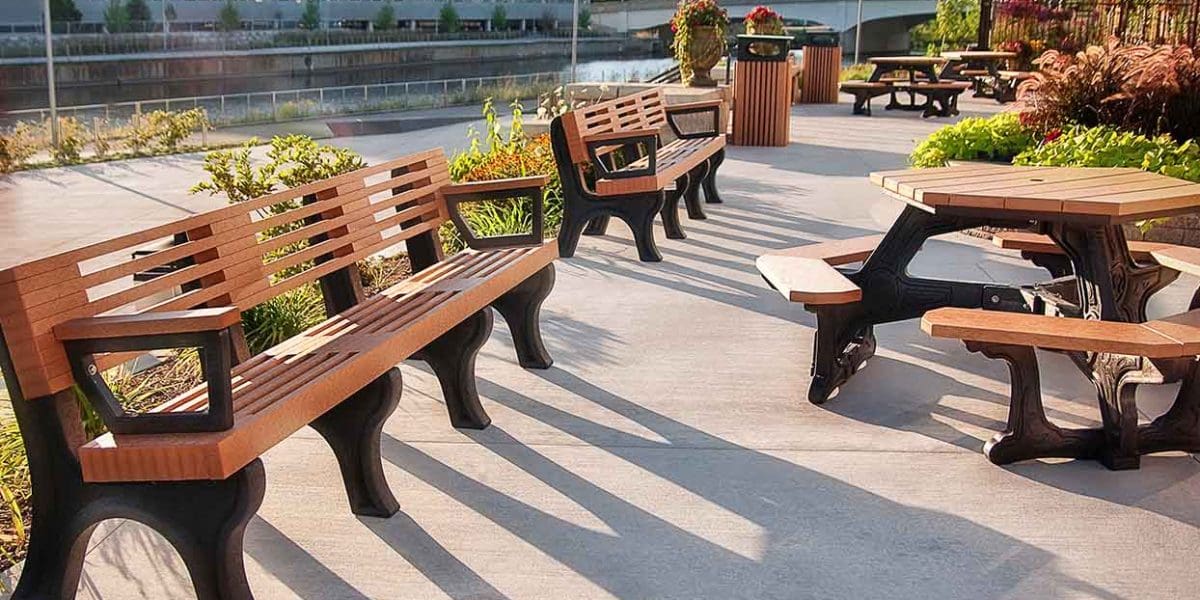 Lansing Market public area furnished with multiple Elite 8ft Backed Benches with arms with black legs & cedar board, Plaza Hex Tables with black Greenscapes frames and cedar boards, and T40C Tall 40 Gallon Trash Receptacles with black tops and cedar bases- Lansing Market