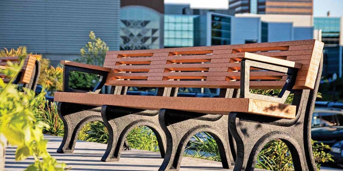 Sunset picture of the Elite 8ft Backed Bench with arms with black legs and cedar board, placed in the Garden - Lansing Market